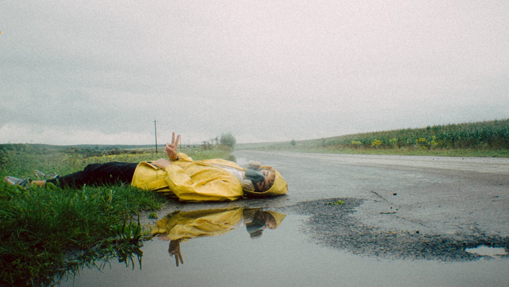 a person laying on the side of a wet road