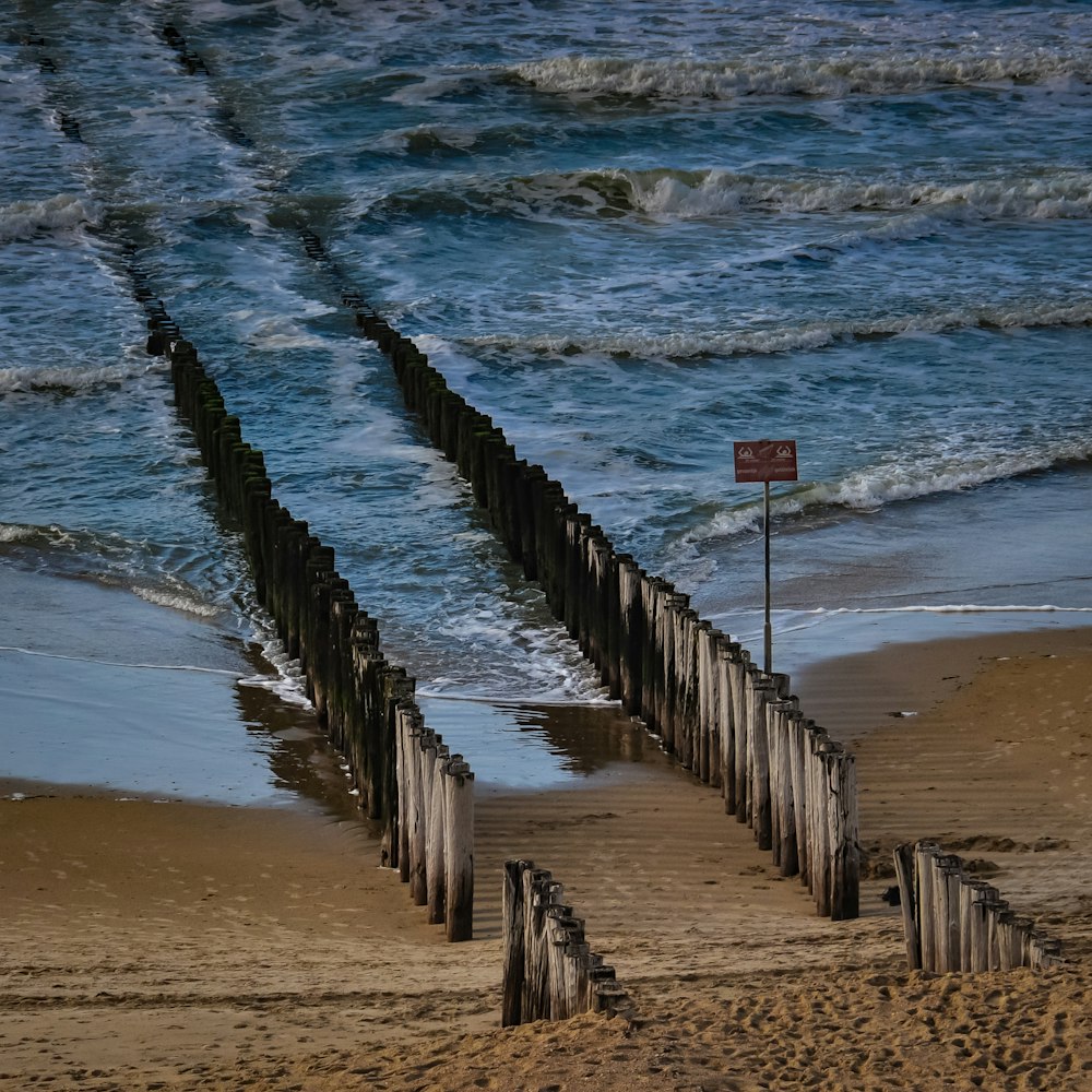 a wooden fence on a beach next to the ocean