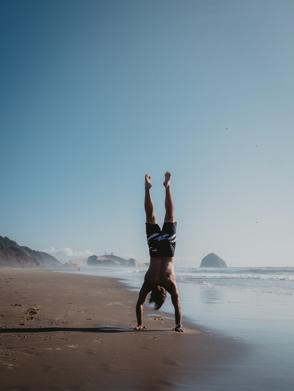 a person doing a handstand on the beach