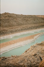 a man standing on top of a hill next to a body of water