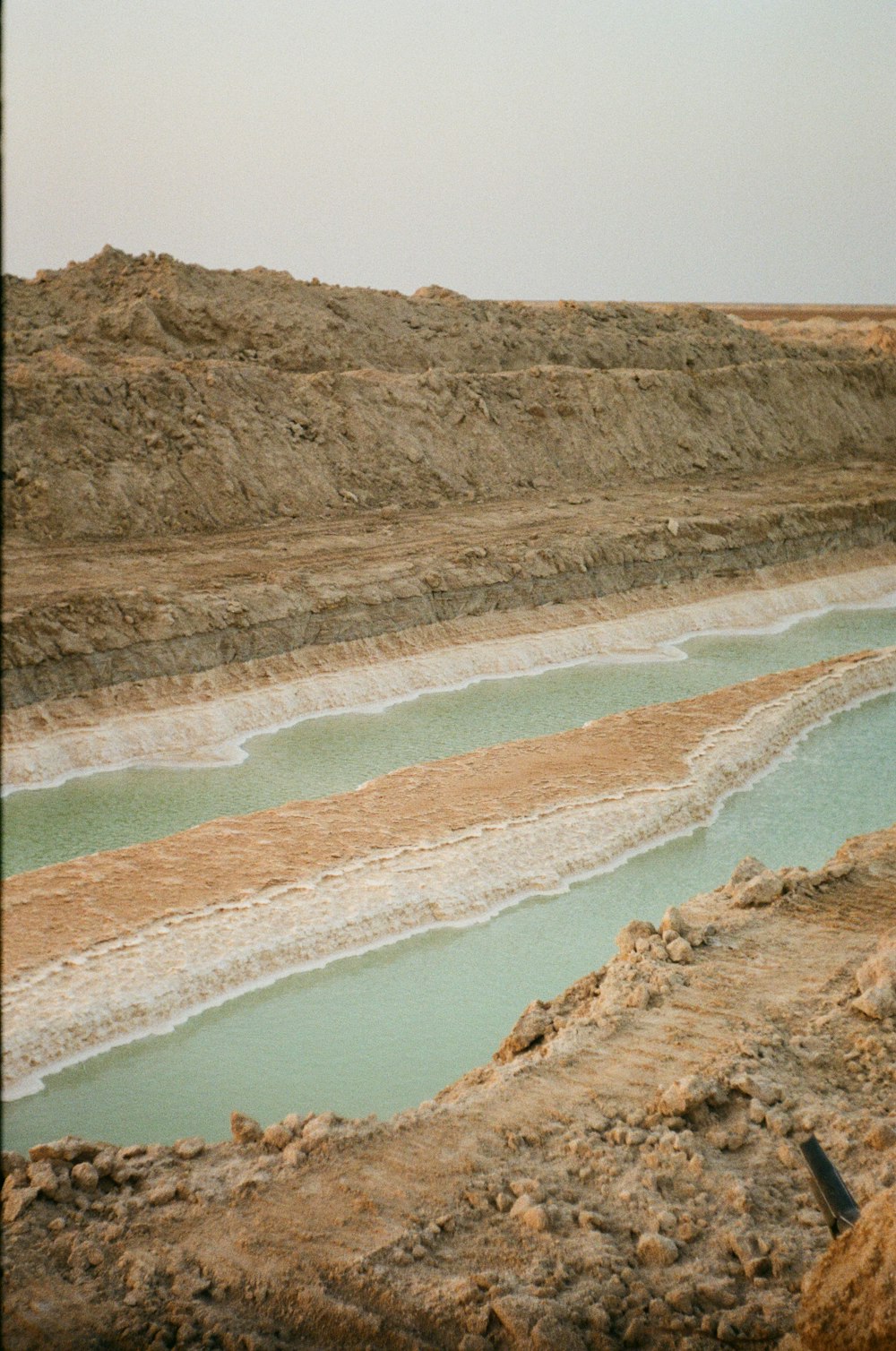 a man standing on top of a hill next to a body of water