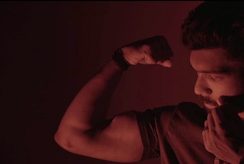 Close-up of a confident man flexing his biceps, veins prominent, embodying raw power.