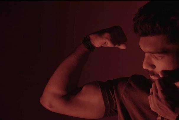 A man proudly flexing his biceps after following MuscleMind's workout plan.