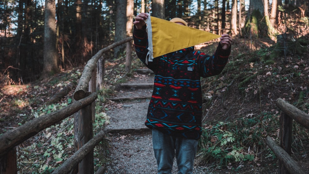 a person holding a yellow kite over their head