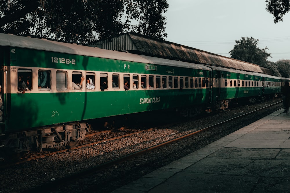 a green passenger train sitting on top of train tracks