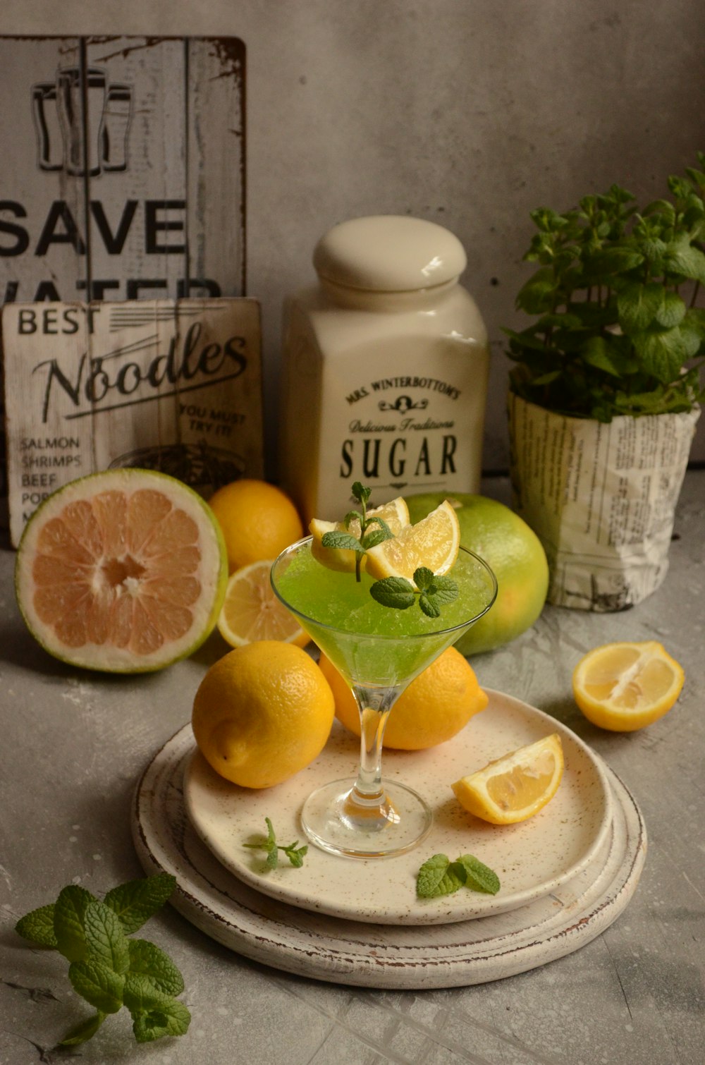 a plate topped with a green drink next to lemons