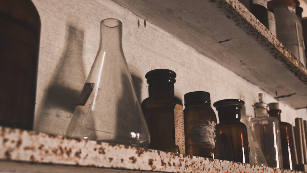 a shelf filled with lots of bottles on top of a wooden shelf