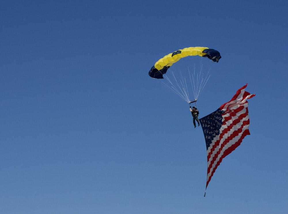 Una persona está navegando en parasailing en el cielo con una bandera estadounidense