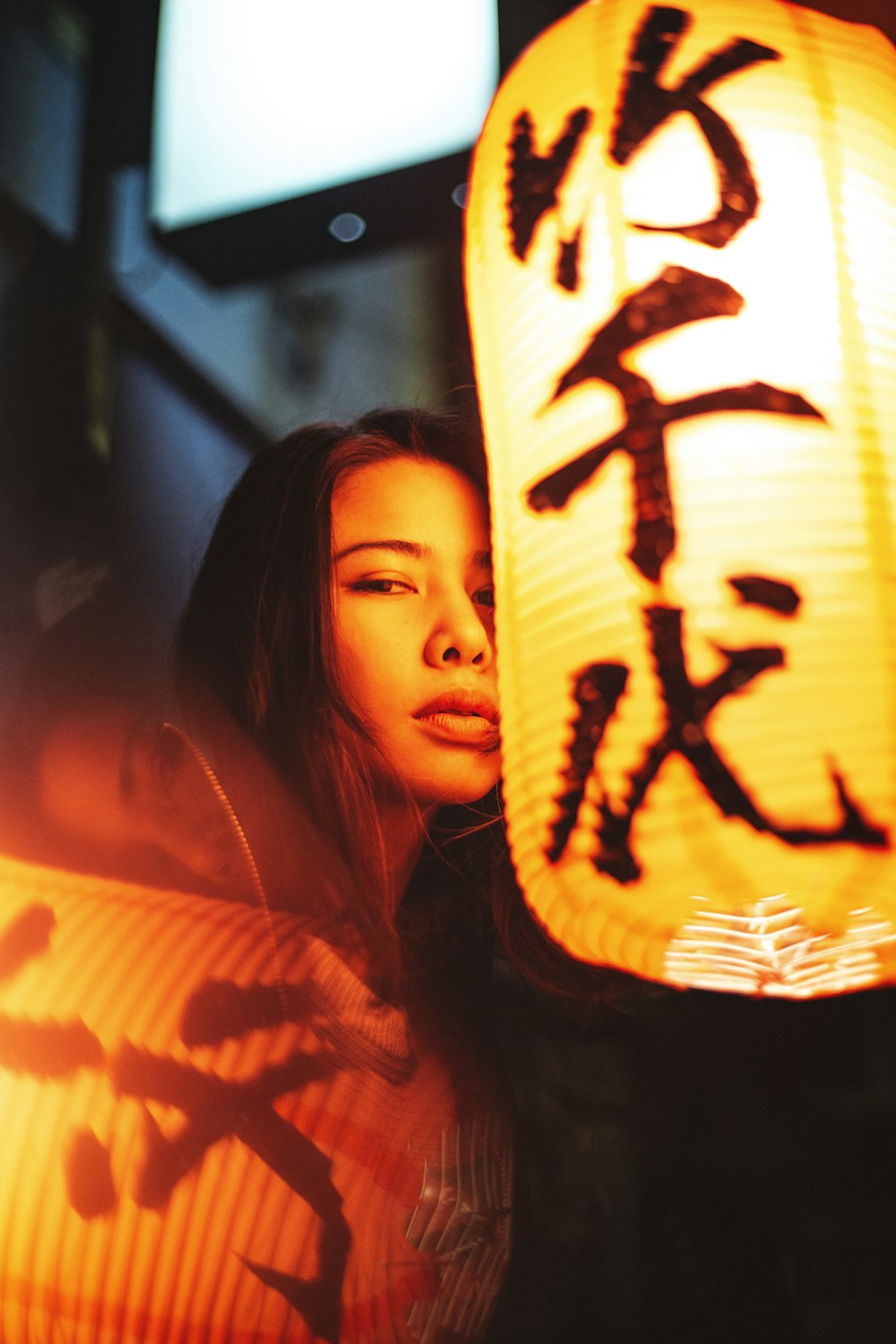 a woman standing next to a lantern with writing on it