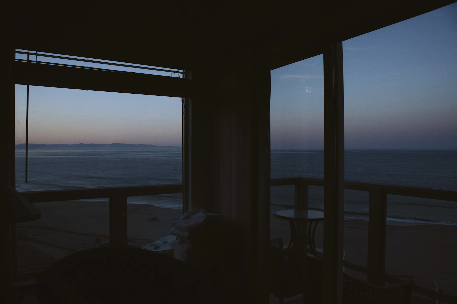 Wooden pier stretching over calm water seen through a window