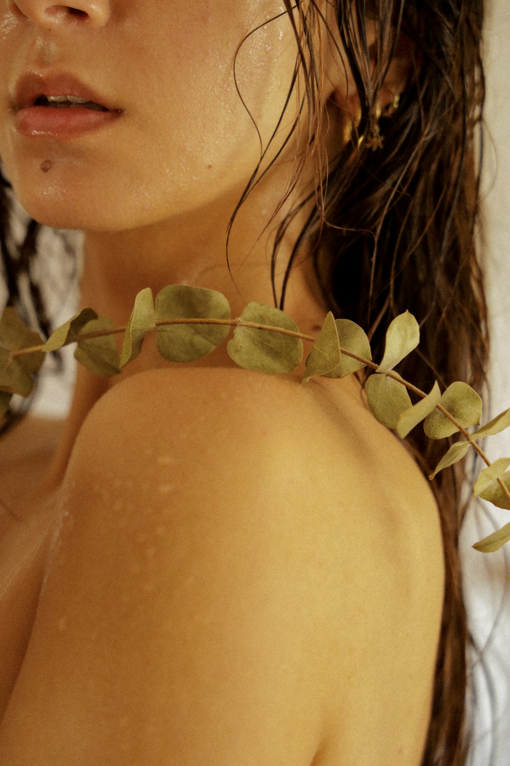 a close up of a woman wearing a necklace with leaves on it