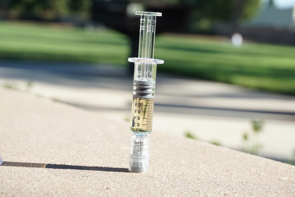 a glass tube filled with liquid sitting on top of a sidewalk