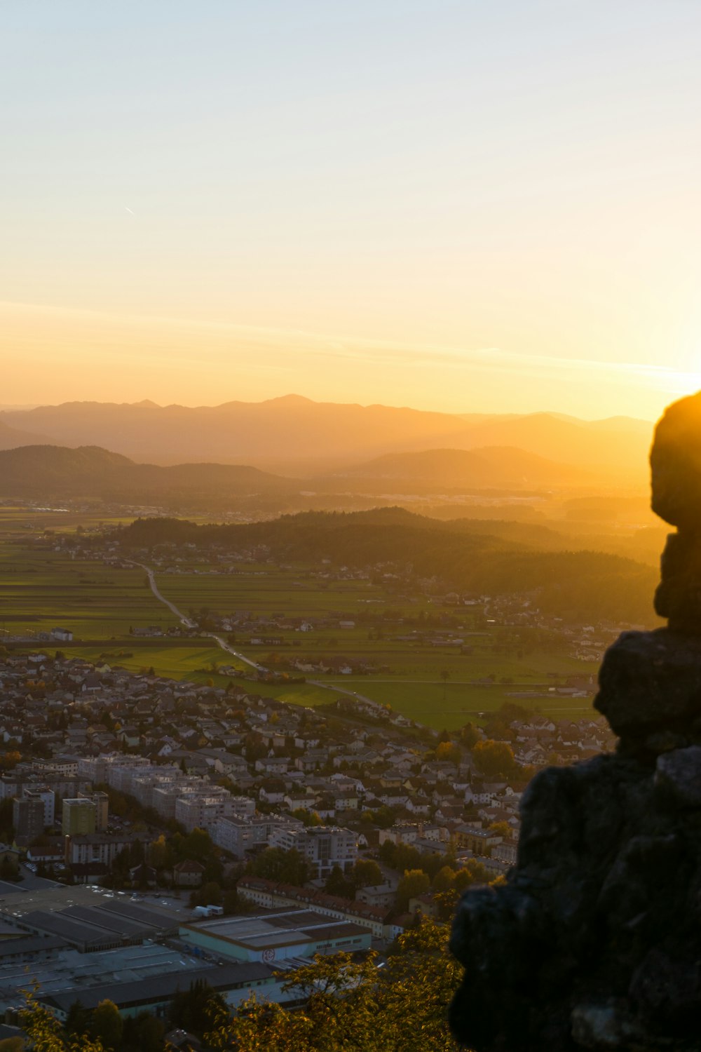 the sun is setting over a city and mountains