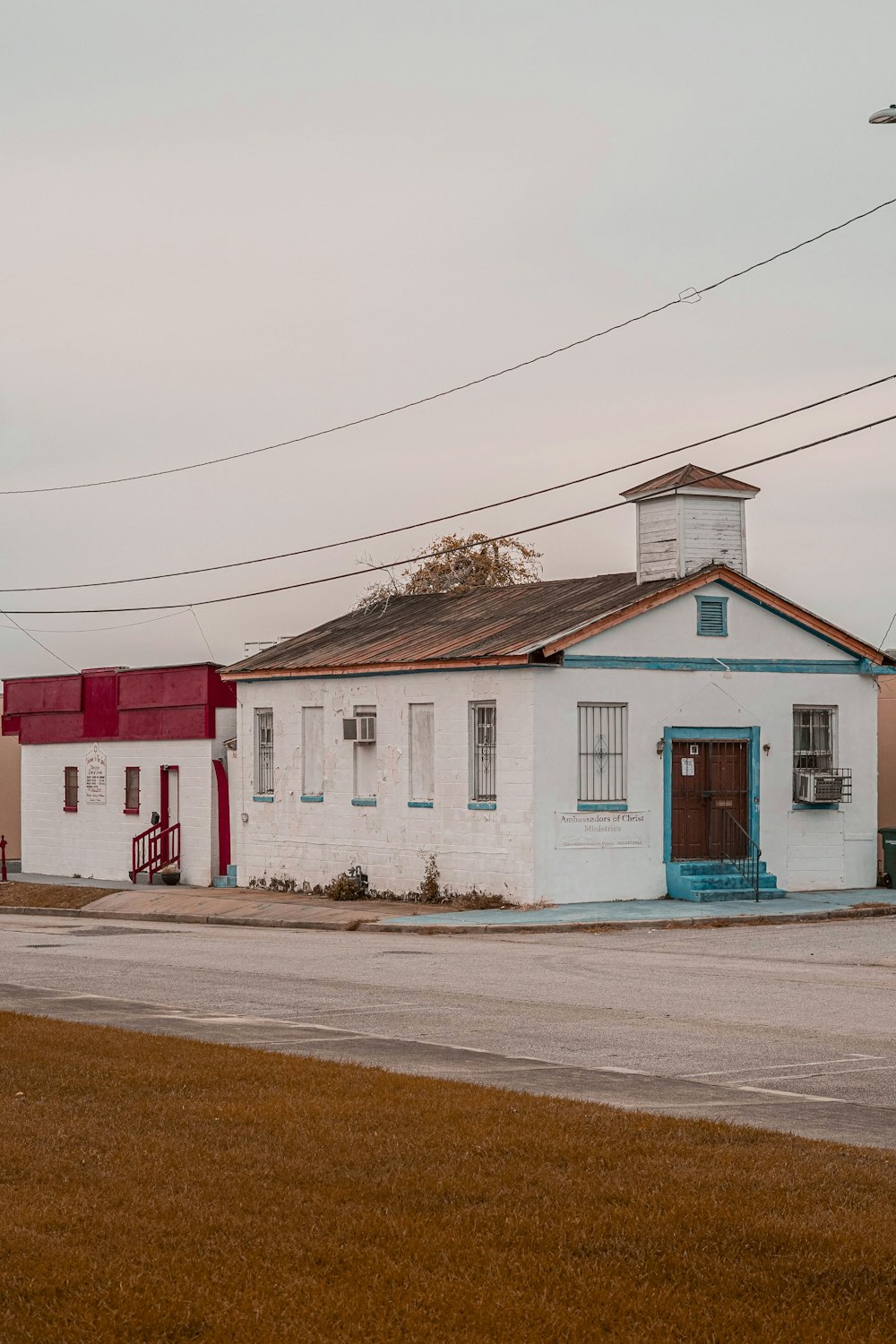 a white building with a blue door and a red door