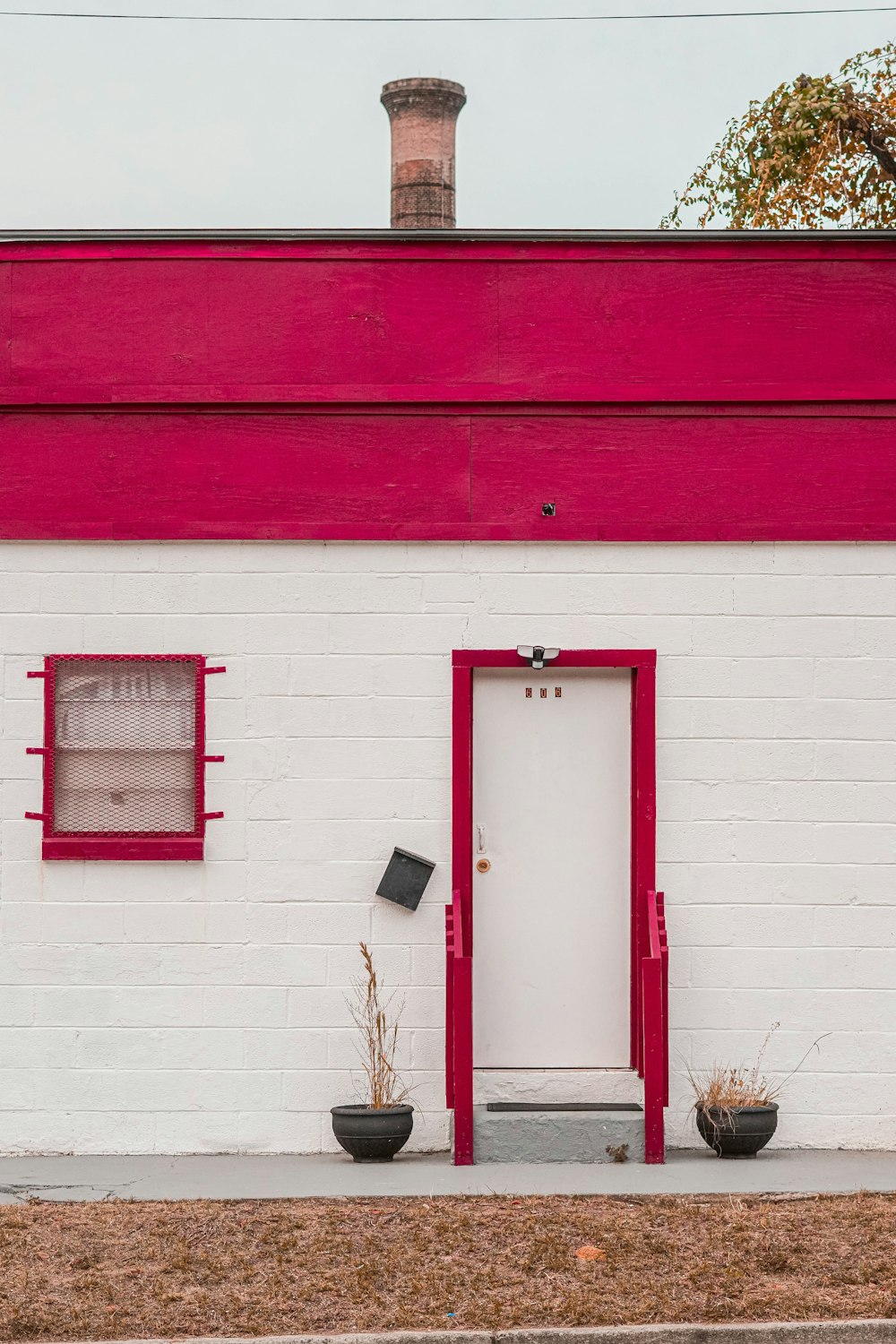 a white brick building with a red door and window