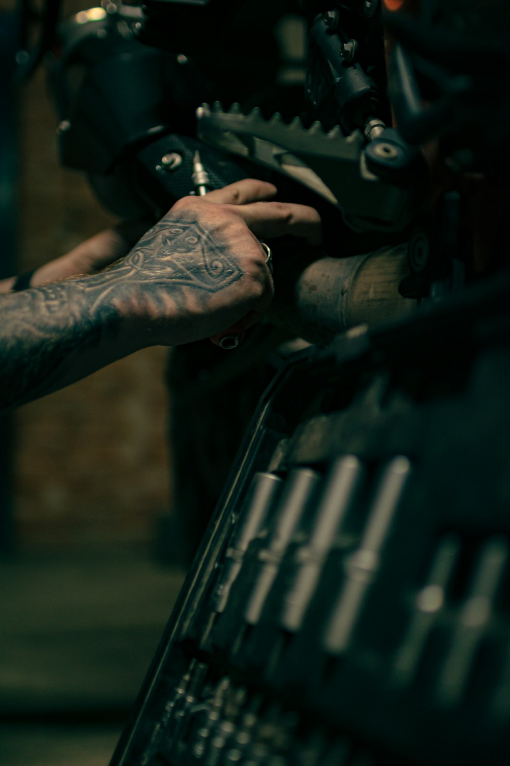 Ein Mann mit einem Tattoo auf dem Arm arbeitet an einem Motorrad