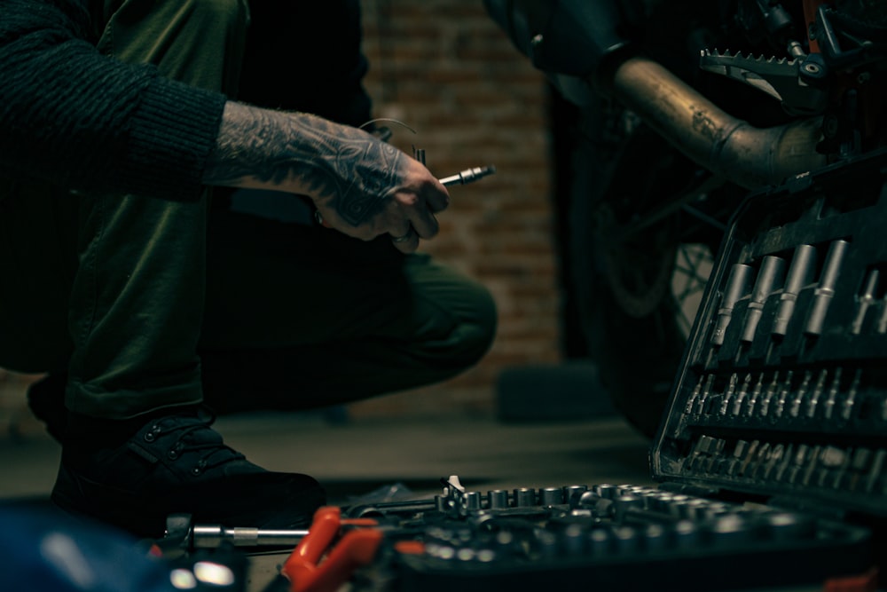 a man sitting on the ground with a cigarette in his hand