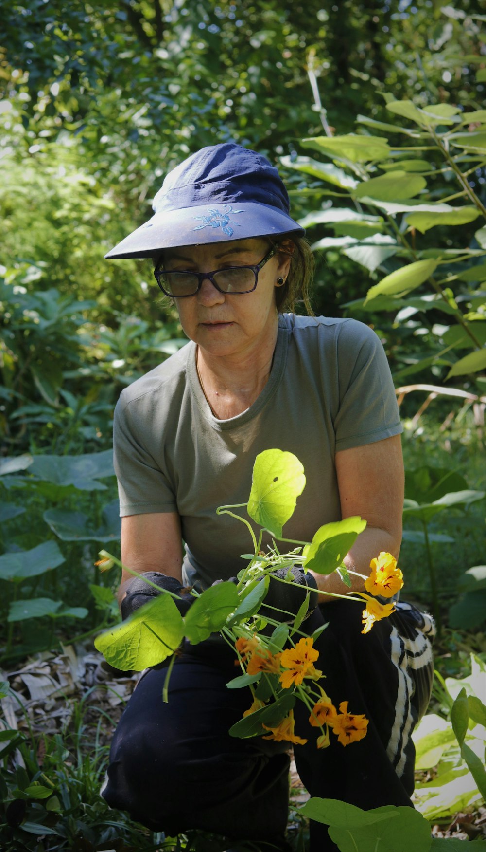 a woman kneeling down in the grass with a plant