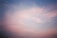 A serene morning sky with soft clouds glowing gently in pastel colors.