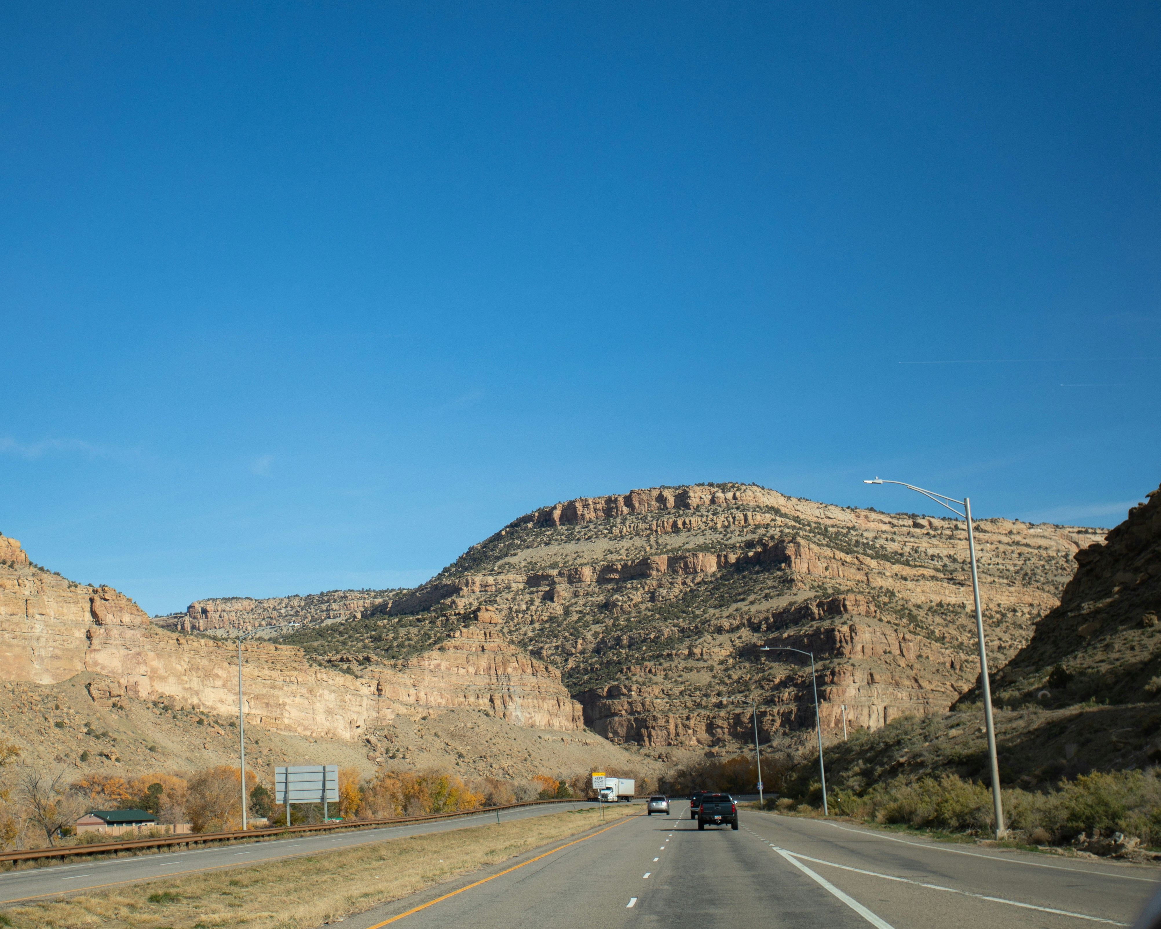 Hero image for Denver to Arches: 4-Day Family Campervan Adventure - a car driving down a highway next to a mountain -  in Rocky Mountains & Northern Rockies - Photo by Logan Gutierrez on Unsplash
