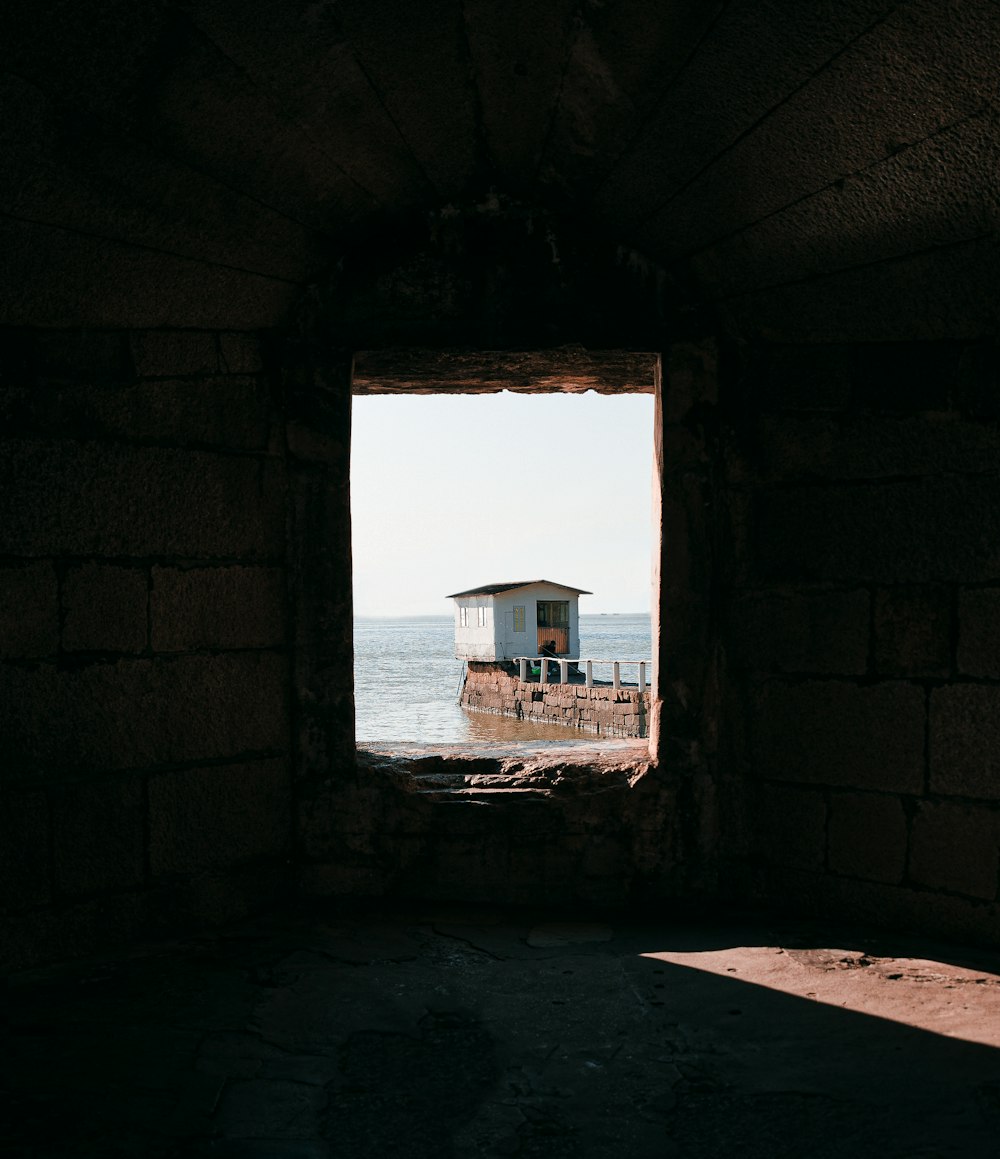 a window in a brick wall looking out at the ocean