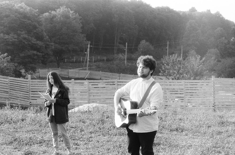 a man holding a guitar standing next to a woman