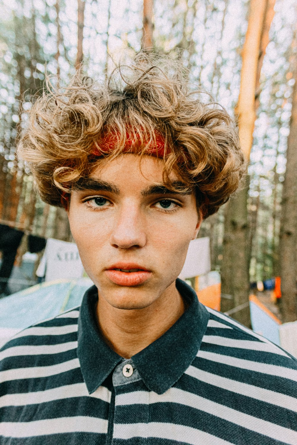 a young man with curly hair and a striped shirt