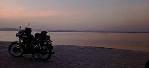 A sleek motorbike parked by a palm-lined beach at sunset in Bali