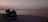 A close-up of a motorcycle parked by a vibrant sunset at the beach.