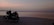 A close-up of a motorcycle parked by a vibrant sunset at the beach.