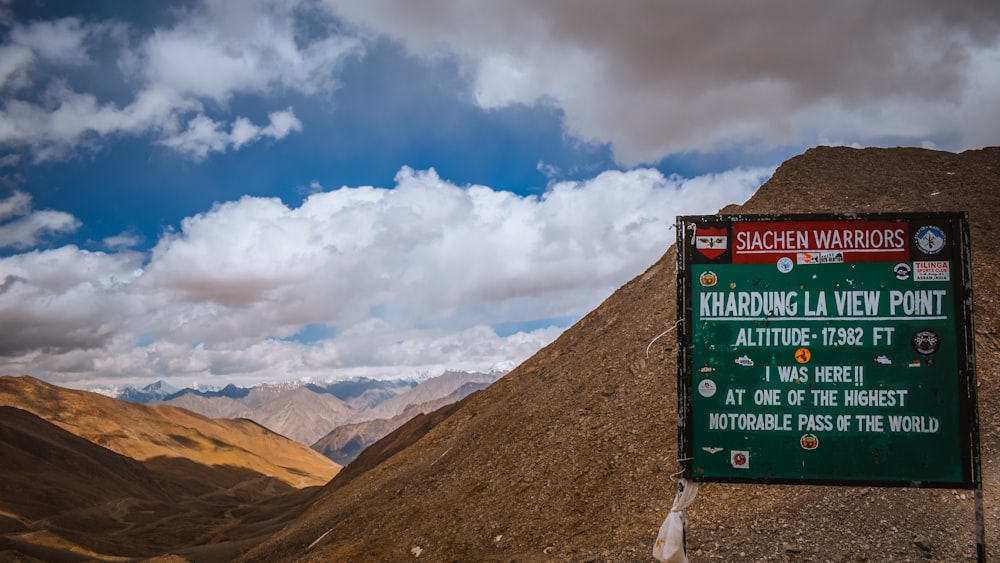 a sign on the side of a mountain with mountains in the background