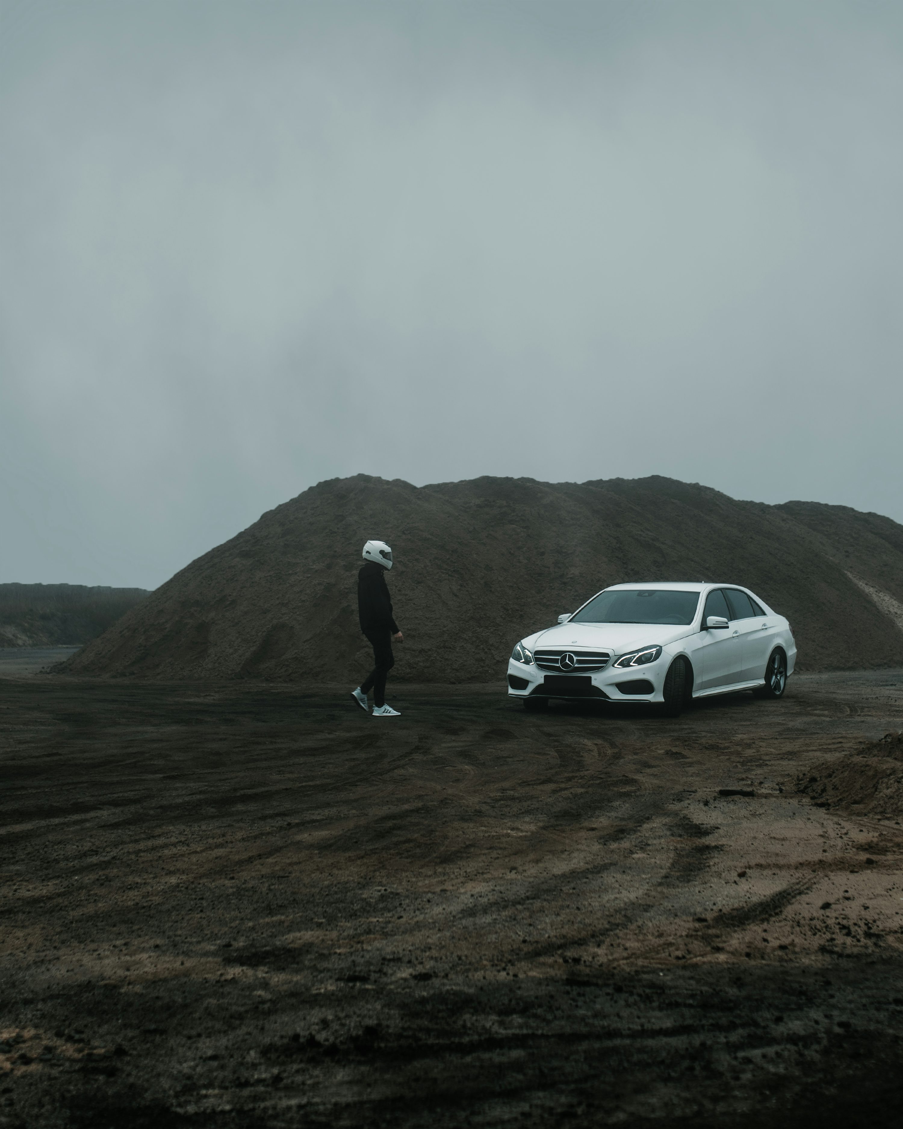 a person standing next to a white car on a dirt road