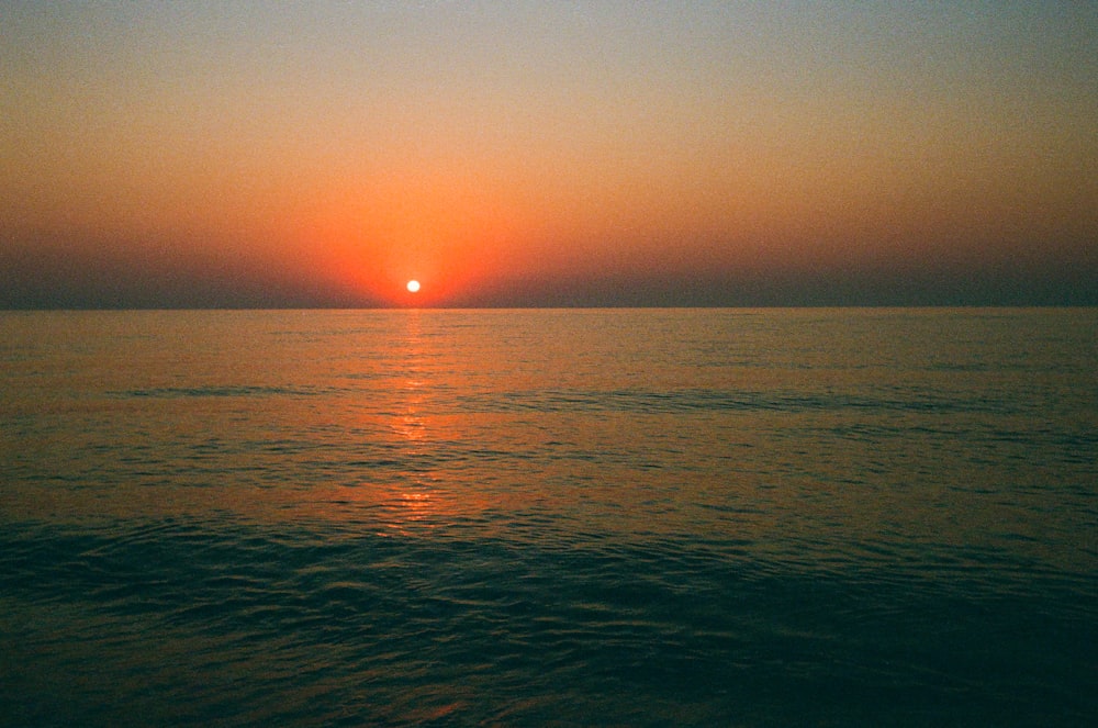 the sun is setting over the ocean on a clear day