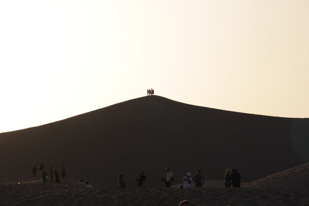 a group of people standing on top of a sandy hill