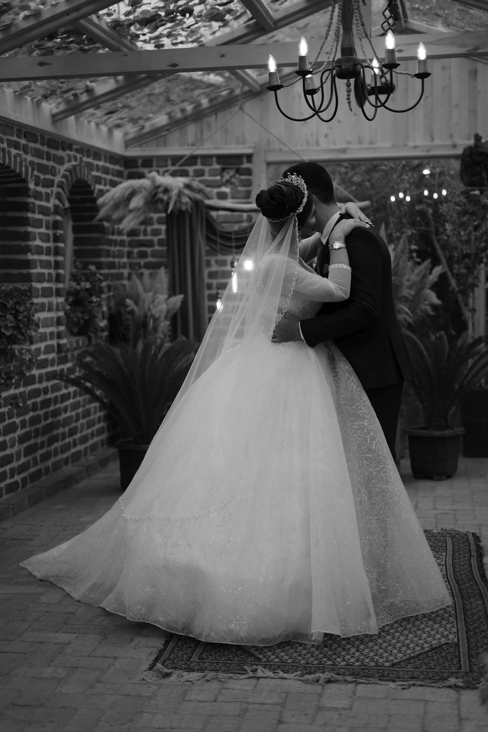 a bride and groom kissing under a chandelier