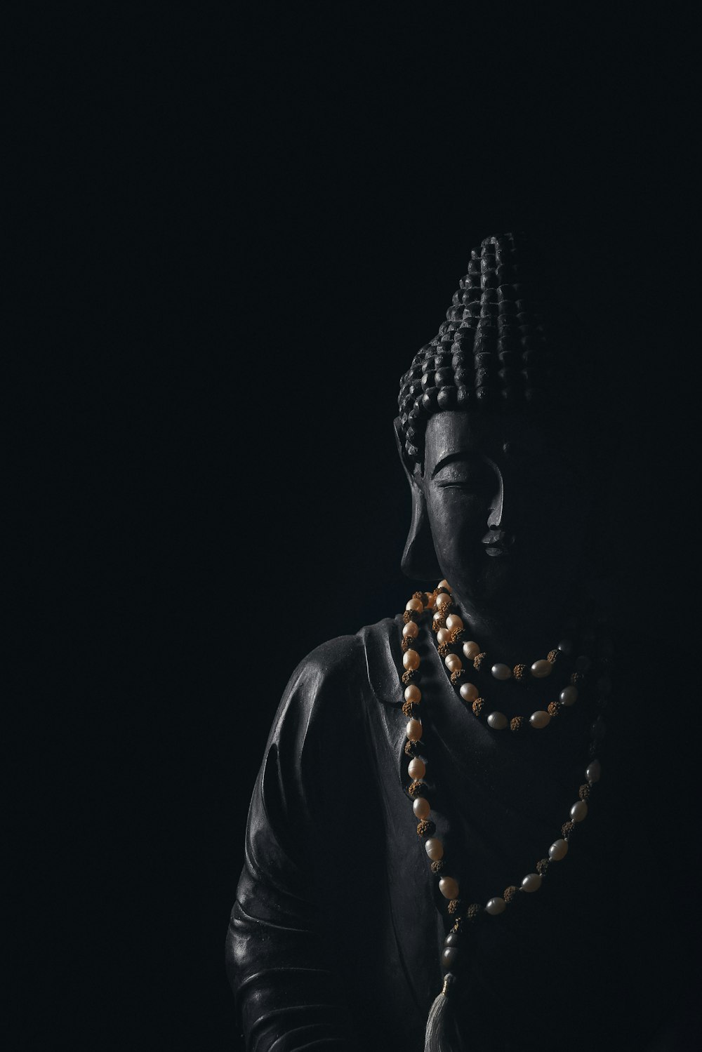 a buddha statue with beads around its neck