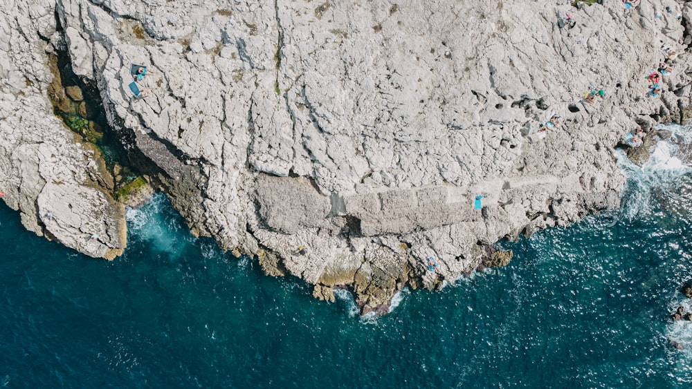 an aerial view of a rocky coastline with people swimming in the water