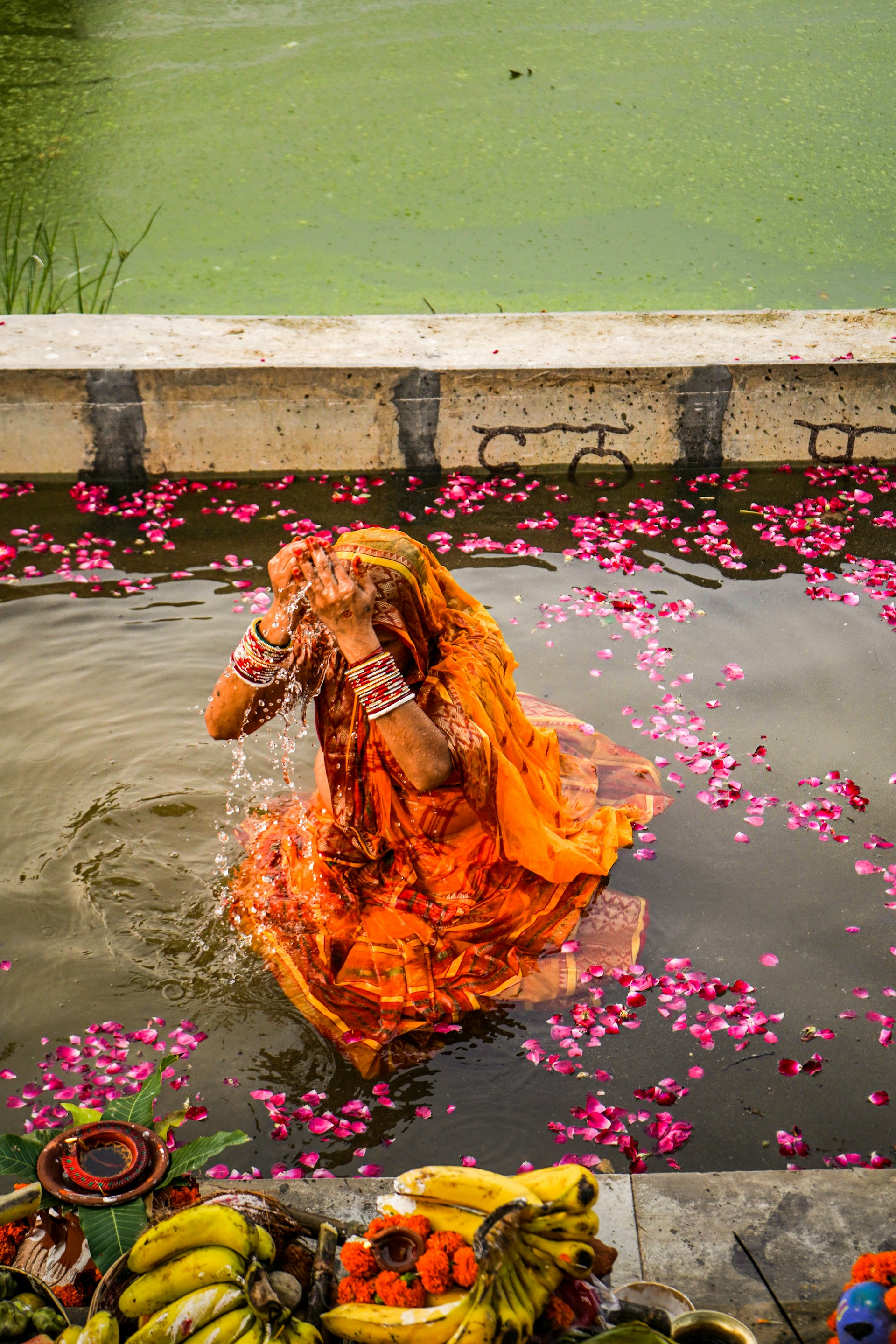 a woman in an orange dress splashes water into a body of water