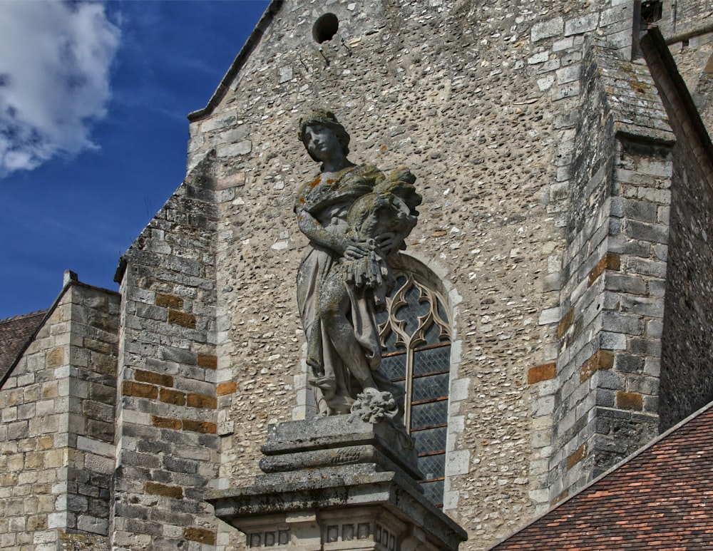 a statue of a woman holding a bird on top of a building