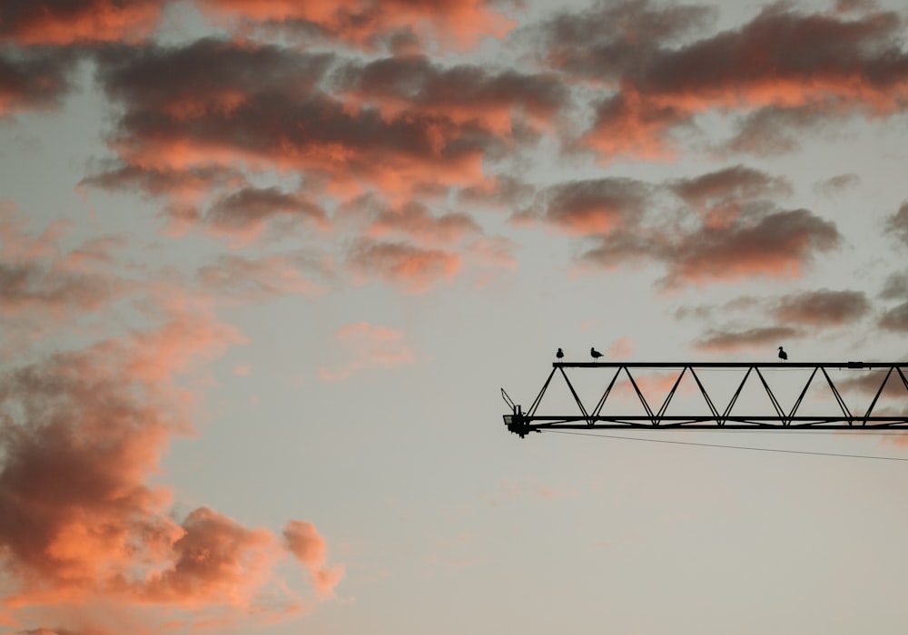 a crane is silhouetted against a cloudy sky