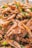 A close-up view of cooked shrimp mixed with chopped green onions. The shrimp is lightly browned, with visible eyes and seasoning, and the dish appears appetizing and fresh.