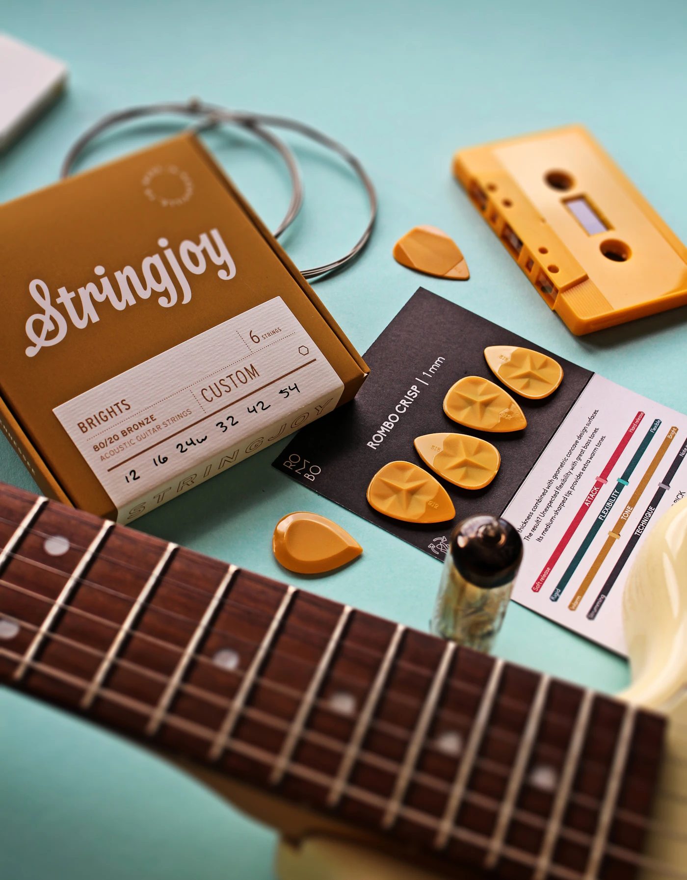 Guitar, notepad, strings, and picks arranged on a table