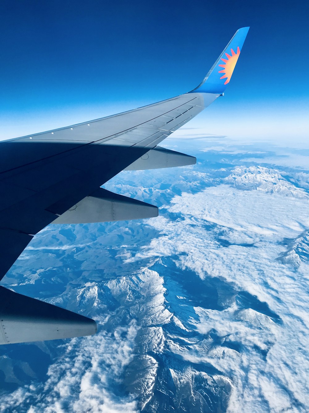 the wing of an airplane flying over a mountain range