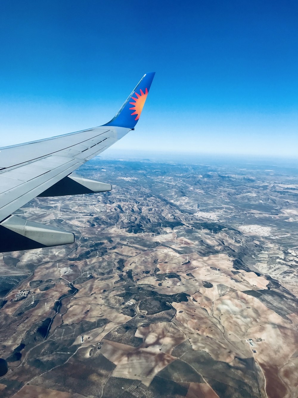 the wing of an airplane flying over a land area