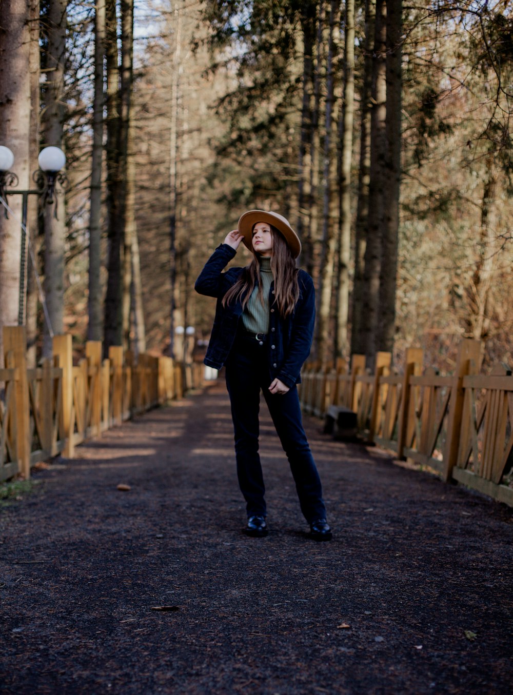 a woman wearing a hat standing in the middle of a road