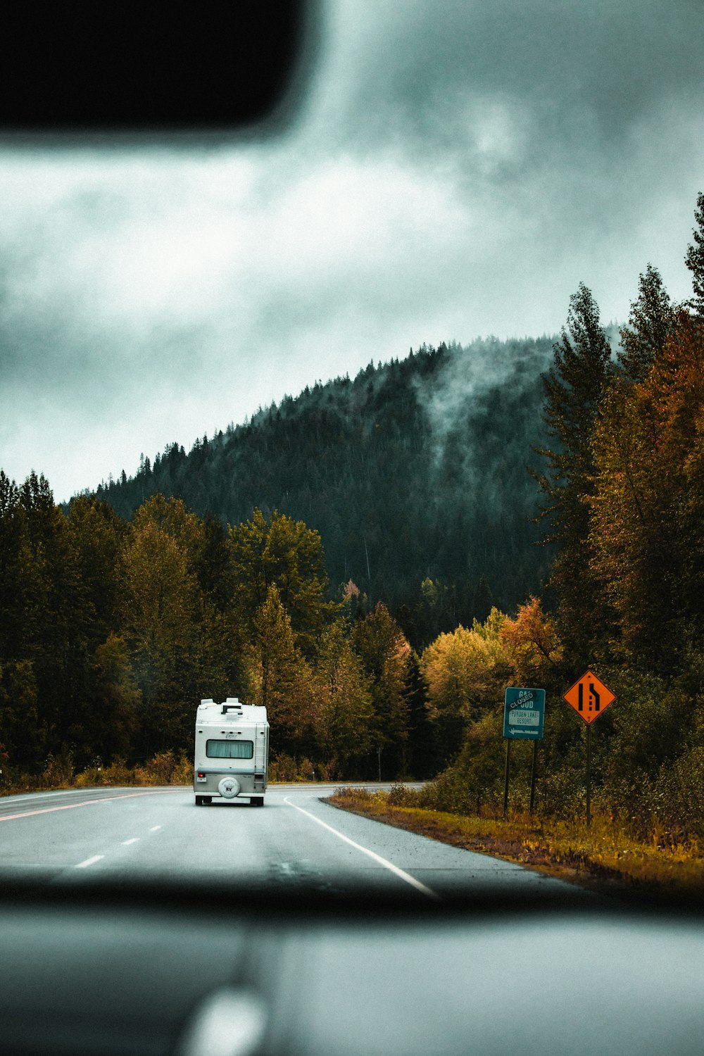 a van driving down a road next to a forest