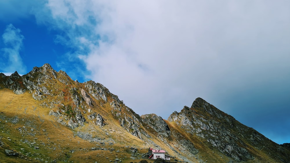 a house on the side of a mountain under a cloudy sky