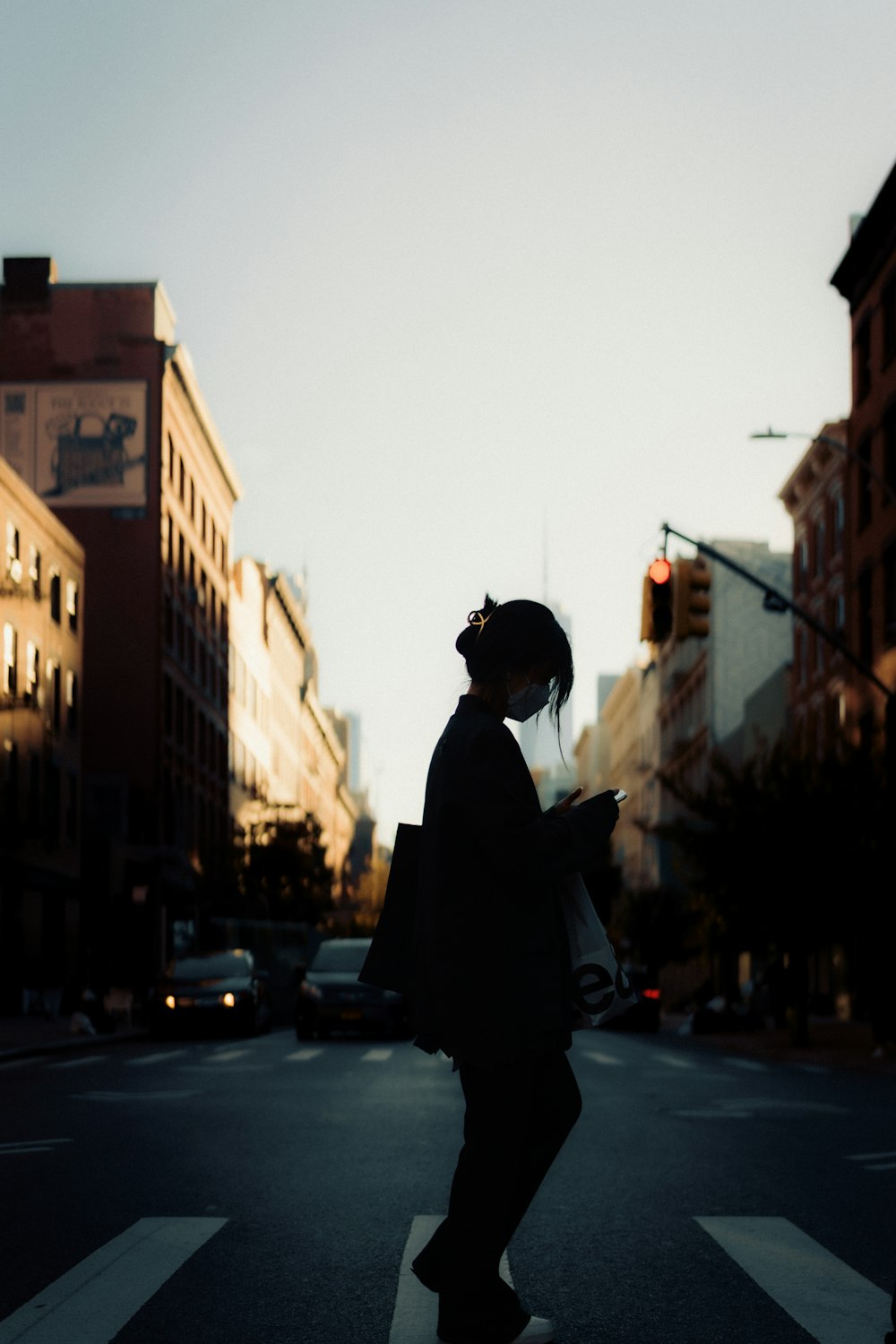 a woman walking across a street holding a cell phone