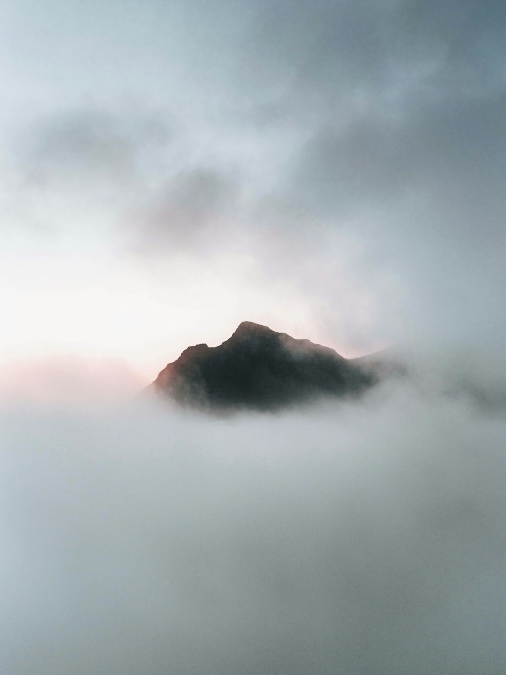 a mountain covered in fog and clouds on a cloudy day