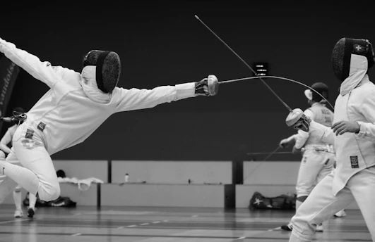 Focused adult fencers sparring in a dynamic competition setting.